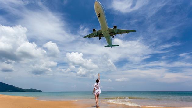 Plane landing at Phuket Airport over a beach. (photo via iStock / Getty Images Plus / southtownboy)